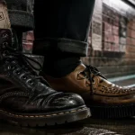 Chaussure punk : bottes de combat et creepers sur trottoir mouillé