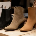 Trois bottines daim : Chelsea, santiag et bottine chaussette sur étal bois clair